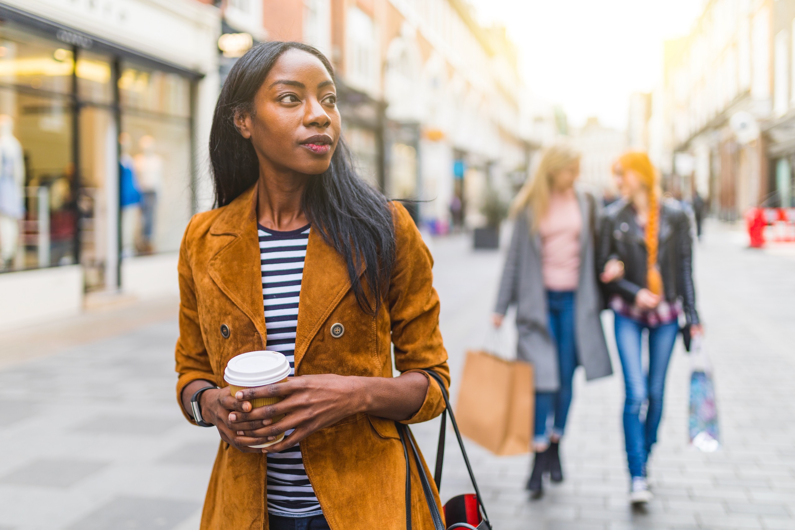 shutterstock_1290589030 woman walking with cup of coffee